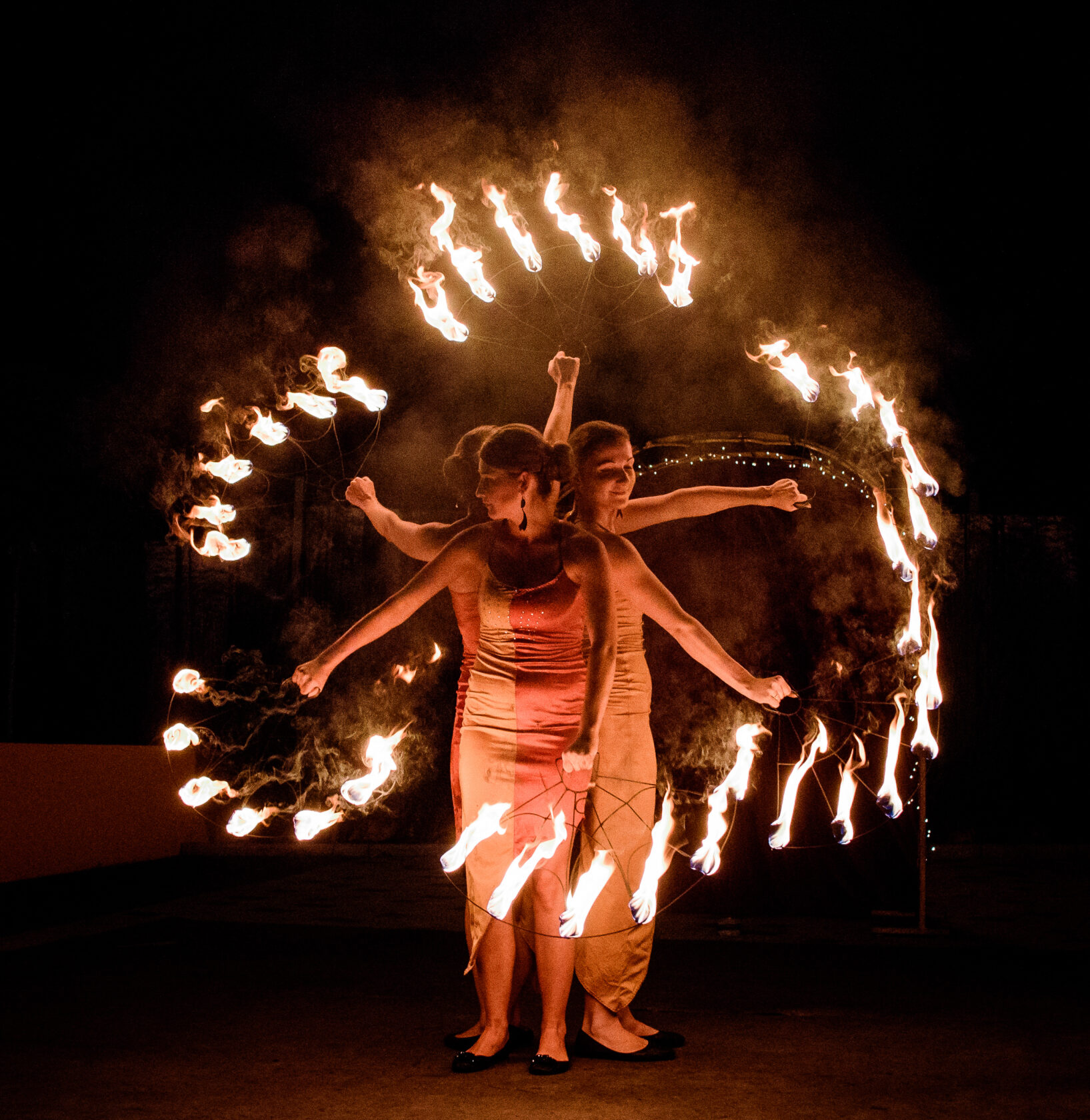 Dancers whirl fire sticks in their hands during the show outside